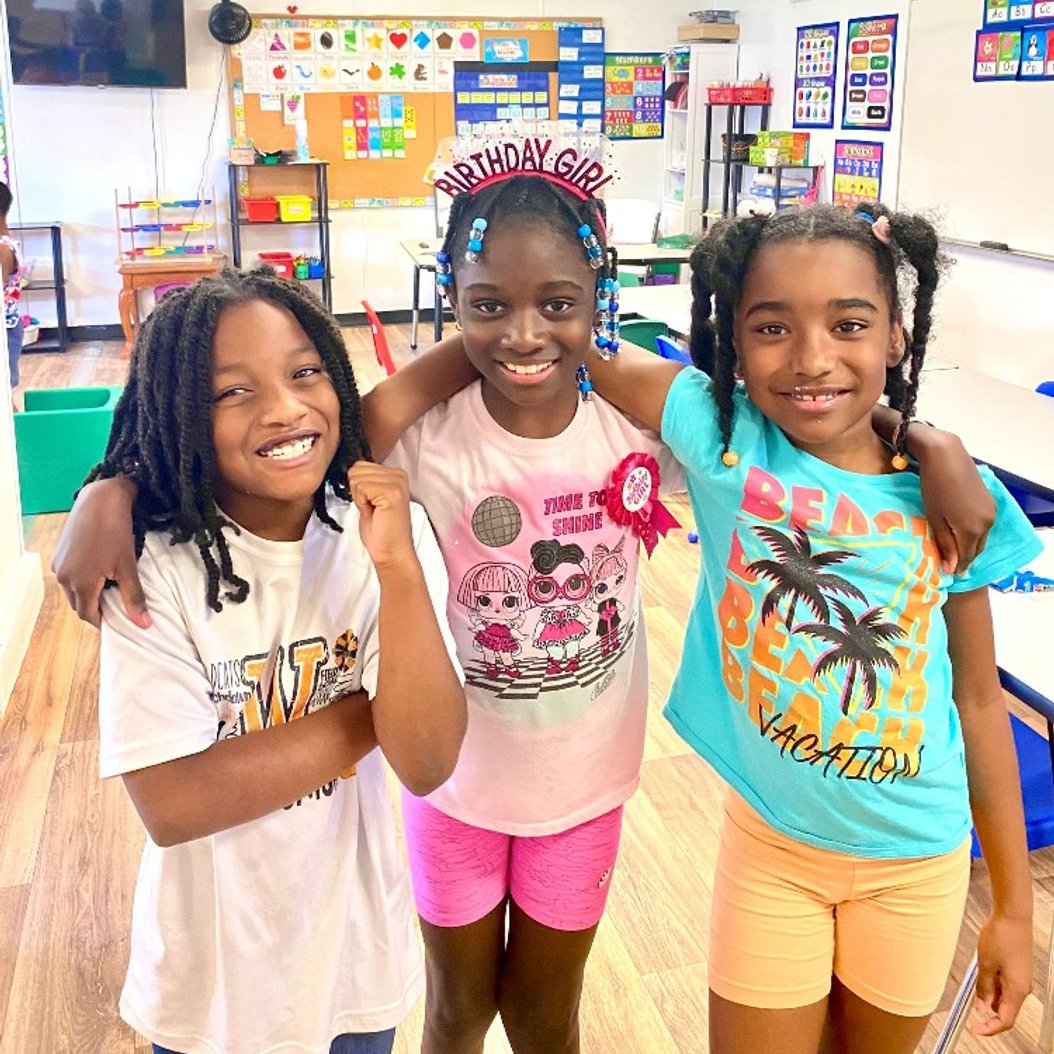 Three kids smiling in a classroom during Bright Stars after school program in Valdosta, GA.