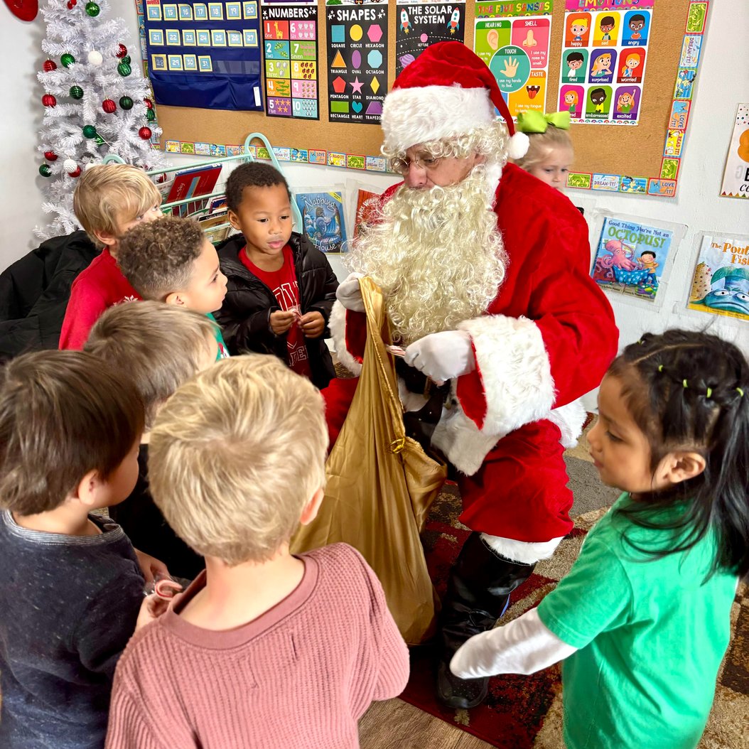 Santa visiting children at Red Trolleys Daycare in Valdosta, GA during a holiday celebration in a decorated classroom.