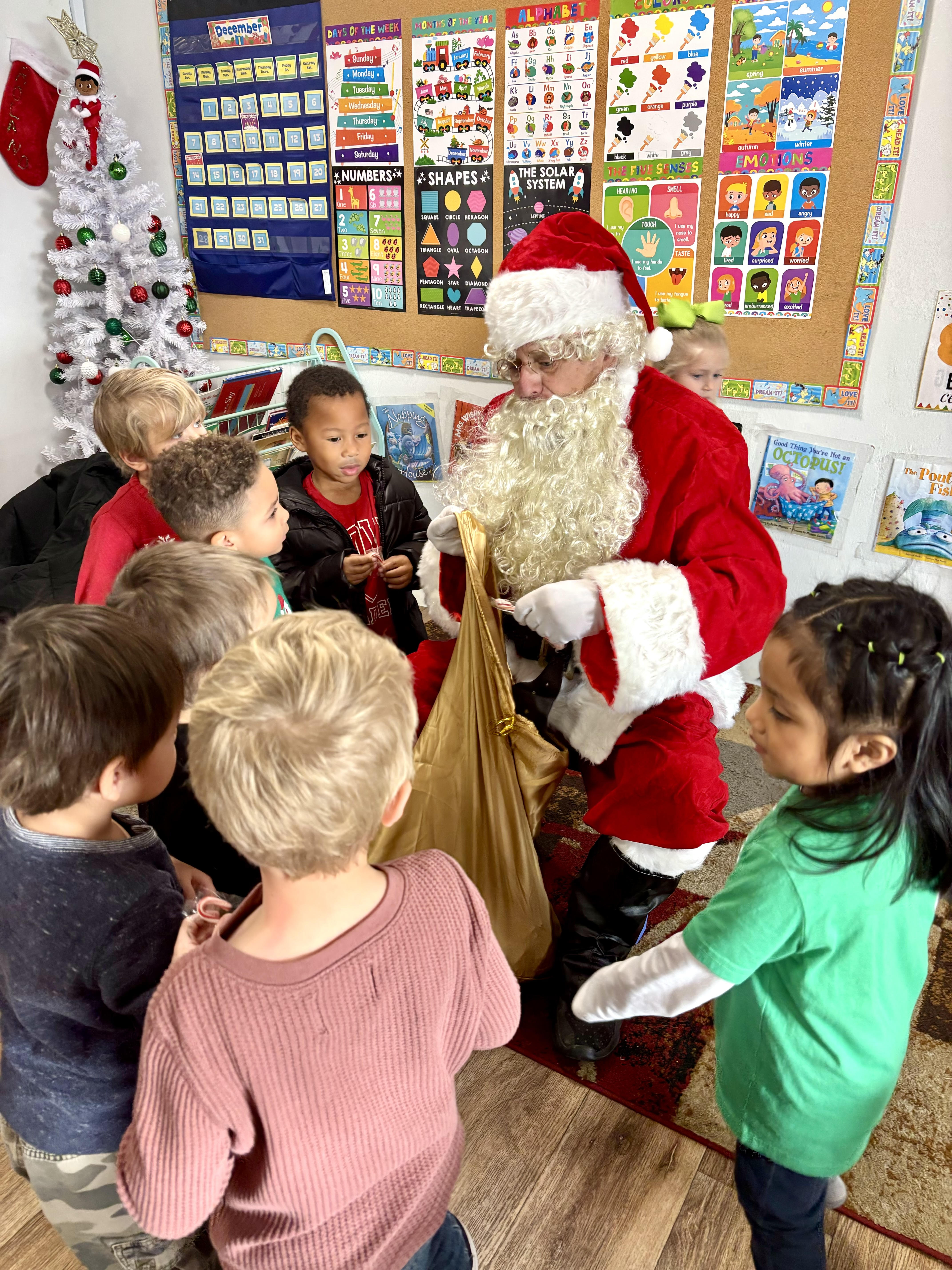 Santa visiting children at Red Trolleys Daycare in Valdosta, GA during a holiday celebration in a decorated classroom.
