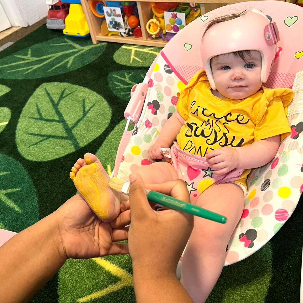 Child at Red Trolleys Daycare in Valdosta, GA enjoying creative foot painting activity.