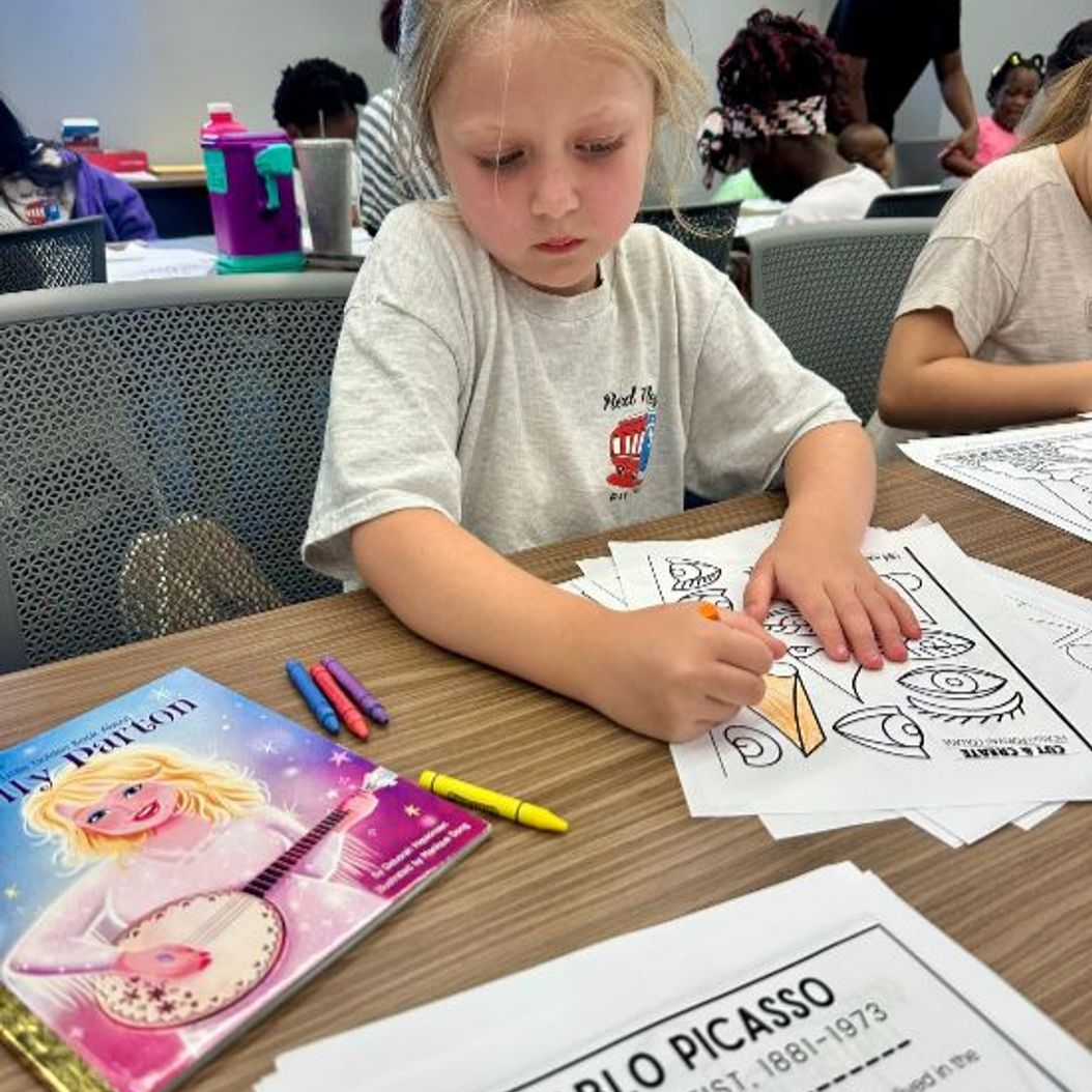 Child coloring at Red Trolleys Daycare in Valdosta, GA, promoting nurturing preschool and school-age programs.