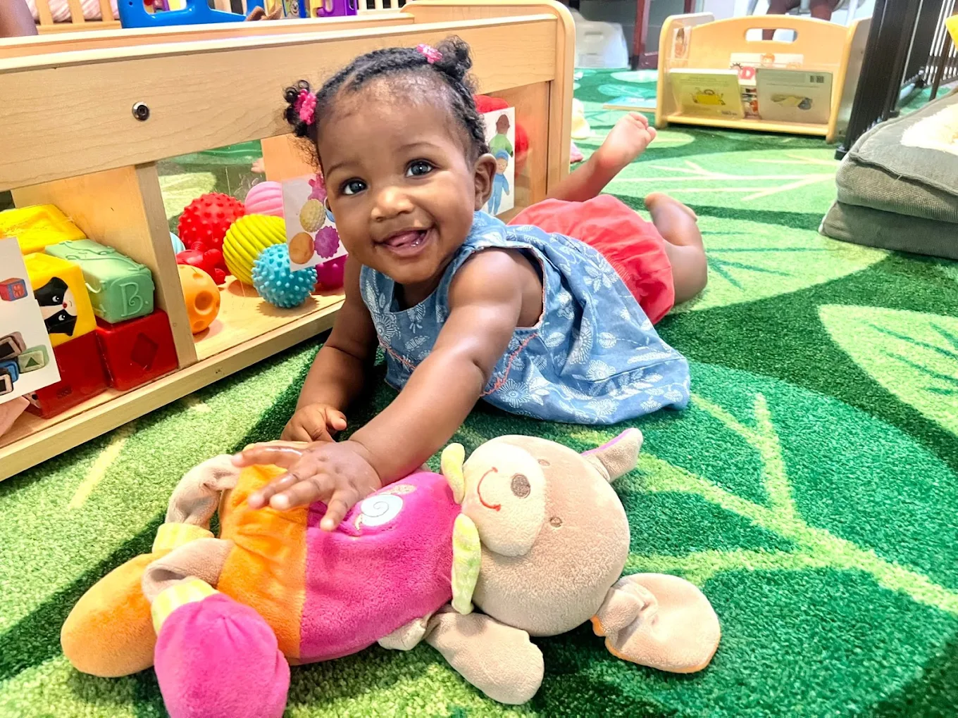 Smiling infant playing with toys at a nurturing care center in Valdosta, GA, for ages 6 weeks to 12 months.
