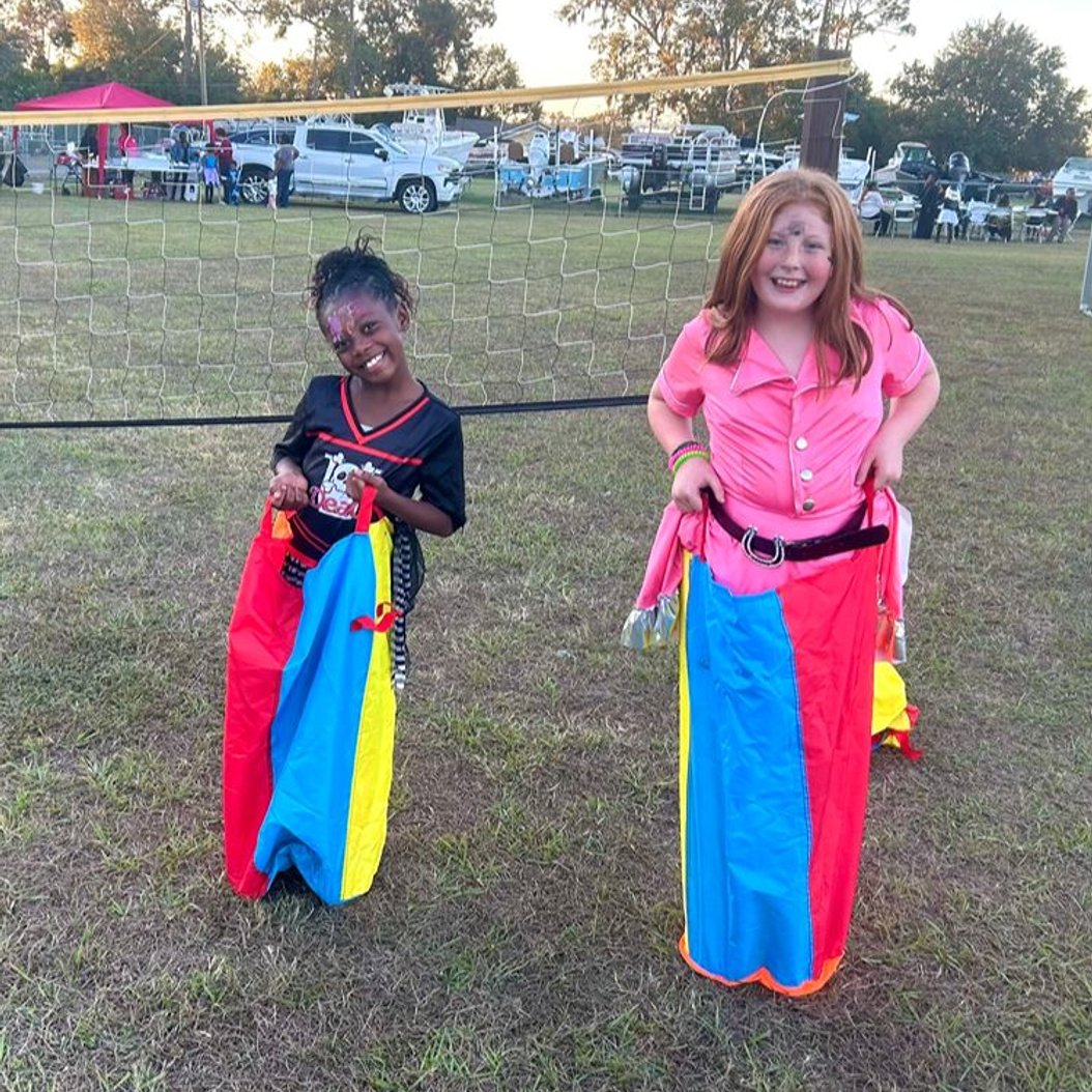 School-age children enjoying a sack race during outdoor games at Red Trolleys Daycare in Valdosta, GA.