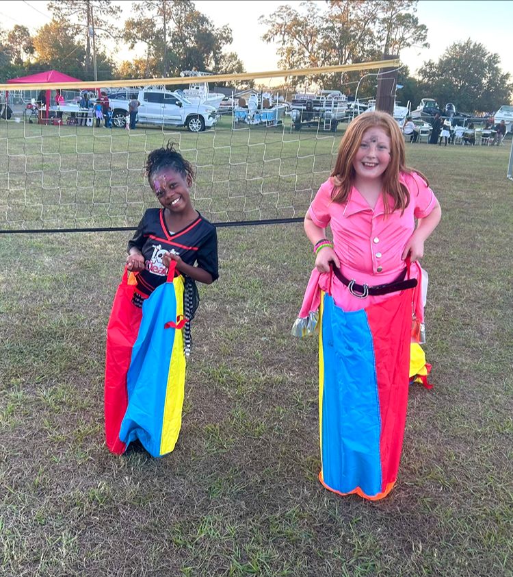 Two children enjoying a sack race at a Red Trolleys Daycare fall festival in Valdosta, GA.