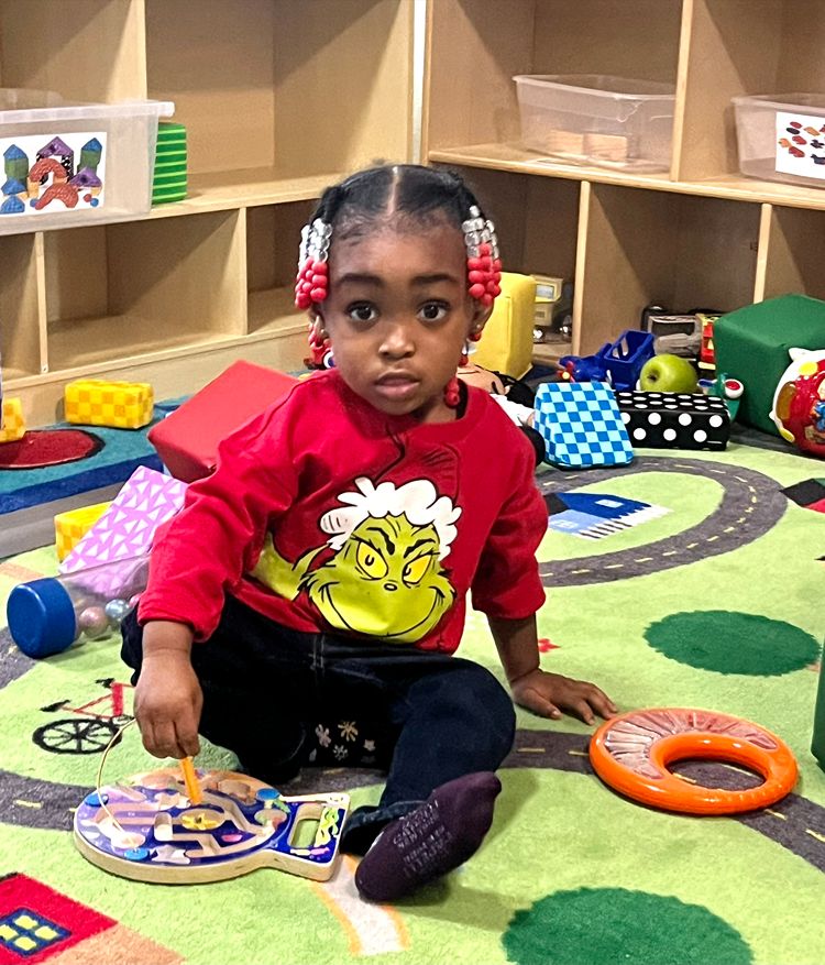 Toddler exploring a wooden maze toy on the classroom rug at Red Trolleys Daycare in Valdosta, GA.
