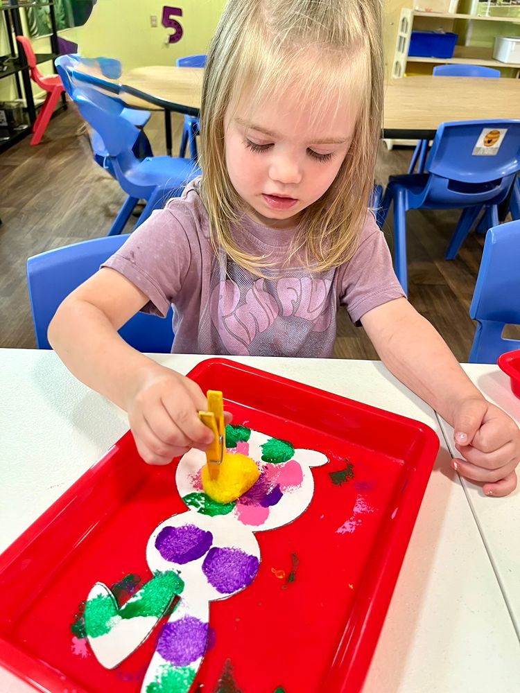 Preschooler creating sponge-painted artwork at Red Trolleys Daycare in Valdosta, GA.