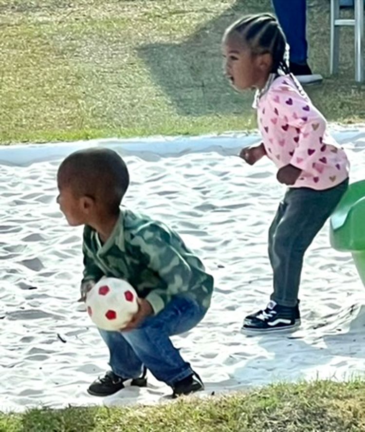 Toddlers playing with a ball in the sandbox at Red Trolleys Daycare in Valdosta, GA.
